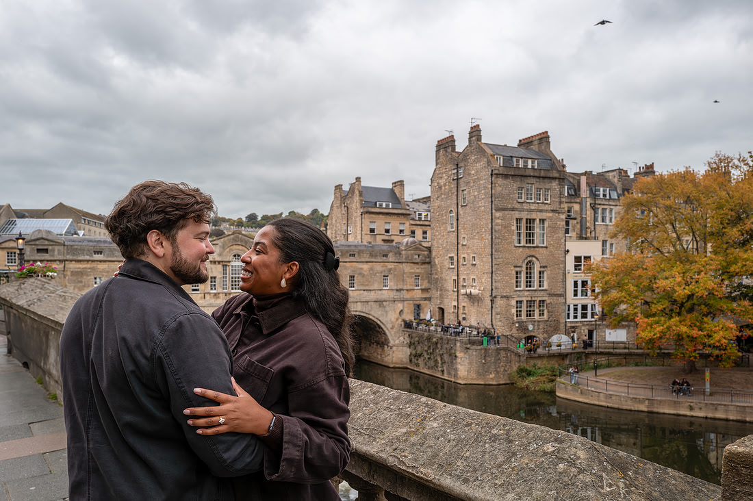 couple standing outside Pulteney Bridge. Engagement & Proposal pictures captured by Bath best photographer. Beata Cosgrove Photography