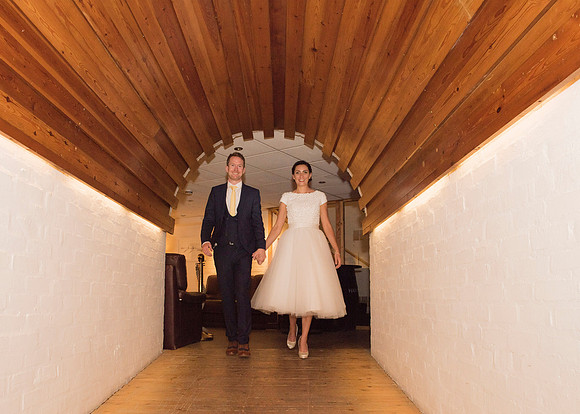 bride and groom walking together down arched corridor