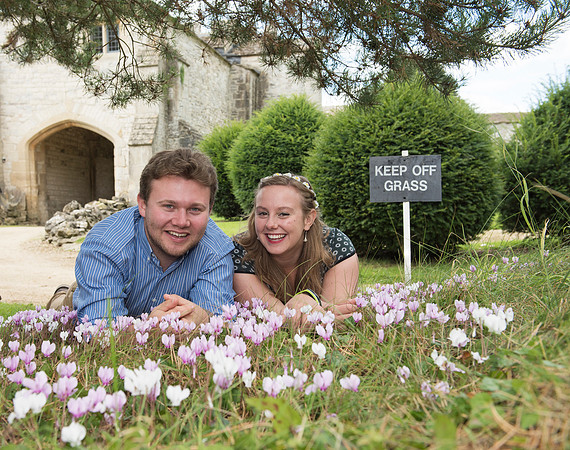 Happy loving couple lying on grass surrounded by flowers