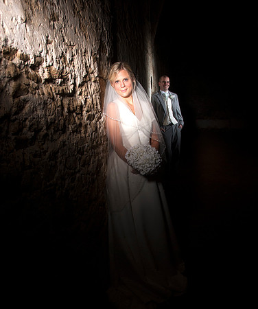 Bride illuminated by ray of light; groom in background