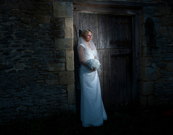 Bride in white dress holding flowers in barn