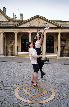 Candid proposal scene outside Bath’s Roman Baths, featuring a romantic moment between a couple with ancient stone architecture behind them. Bath photographer